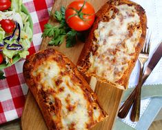 two slices of pizza sitting on top of a wooden cutting board next to a salad