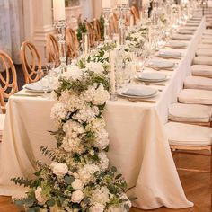 the table is set up with white flowers and greenery for an elegant wedding reception