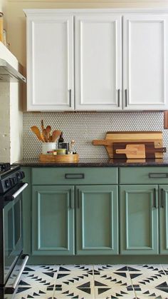 a kitchen with green cabinets and black stove top in the center, on a patterned tile floor