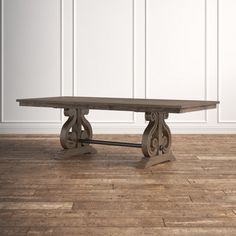 a wooden table sitting on top of a hard wood floor next to a white wall