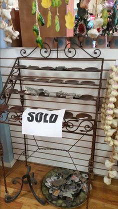 there is a sign that says sold in front of a rack with seashells