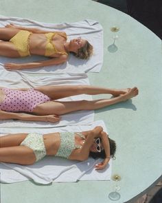 two women in bikinis are laying on towels