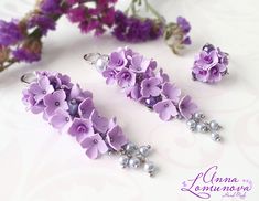 three pieces of jewelry sitting on top of a table next to purple flowers and beads