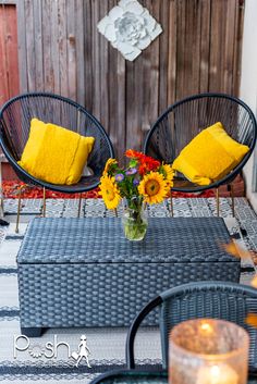 two wicker chairs sitting on top of a table next to a vase filled with flowers