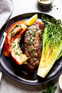 a black plate topped with meat and veggies on top of a white table