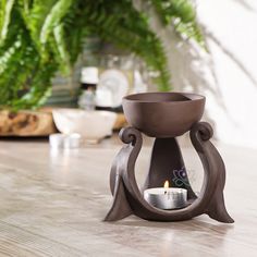 a candle holder sitting on top of a wooden table next to a potted plant