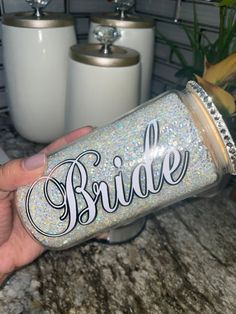 a hand holding a glittered bride tumbler with the word bride written on it