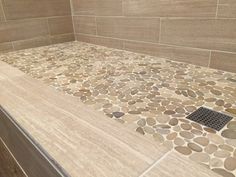 a bathroom with stone flooring and tile on the shower wall, along with a walk in shower