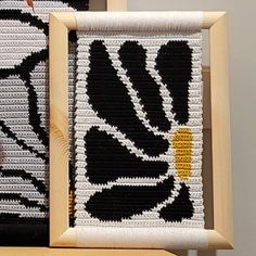 two pieces of knitted art sitting on top of a wooden table next to each other