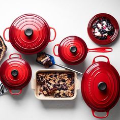 a table topped with red pots and pans filled with food