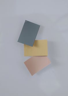 three different colors of paper sitting on top of each other in front of a white wall