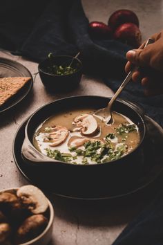 a bowl of soup with mushrooms and spinach on the side next to other dishes