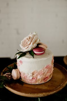 a white cake with pink flowers and macaroons on top