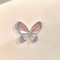 a butterfly brooch sitting on top of a white table next to a pink wall