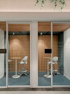 an office with two chairs and a table in front of the glass doors that are open