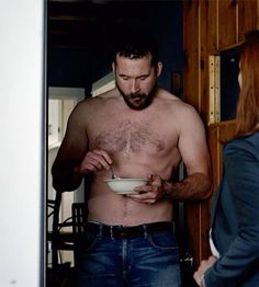 a shirtless man holding a bowl in front of a woman with no shirt on