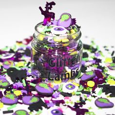 a jar filled with purple and green confetti on top of a white table