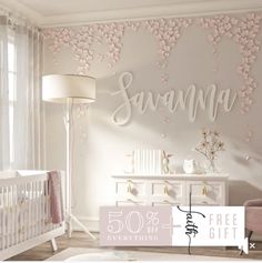 a baby's room with white furniture and pink flowers on the wall above it