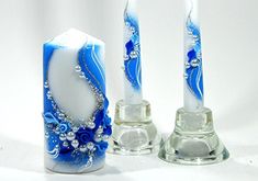 two candles with blue and white designs on them are next to each other in front of a candle holder