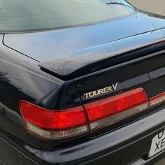 the back end of a black car parked in a parking lot