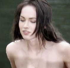 a shirtless woman standing in the water with her eyes closed