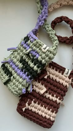 four crocheted bags with tags on them sitting on top of a white table