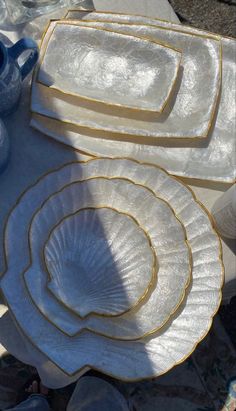 white dishes with gold trim sitting on top of a table next to blue vases