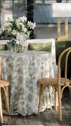 two chairs and a table with white flowers in vases on it at an event