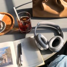 an open book with headphones on top of it next to a cup of tea