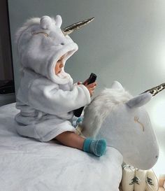 a baby in a unicorn costume playing with a remote control