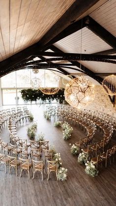 an indoor wedding venue with wooden chairs and chandeliers