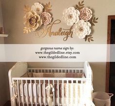 a baby crib with flowers on the wall and a name sign above it that says,