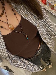 a woman wearing a brown shirt and some necklaces on her neck in a store