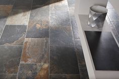 a black and brown tile floor next to a white table with a vase on it