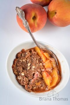 a white bowl filled with food next to two peaches