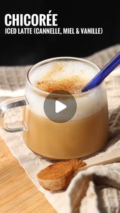 a glass filled with liquid sitting on top of a wooden table next to a spoon