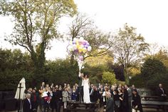 a bride and groom are walking down the street with their wedding party in the background