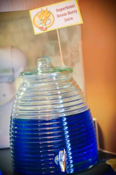 a blue glass vase sitting on top of a table next to a sign that says super - sonic berry juice