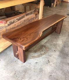 a wooden bench sitting on top of a floor next to a pile of wood planks