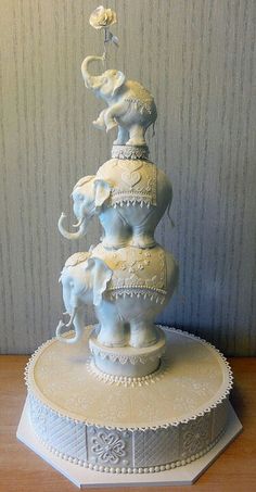 an elephant figurine on top of a cake with elephants and flowers in the middle