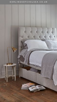 a bed with white linens and pillows in a bedroom next to a table lamp