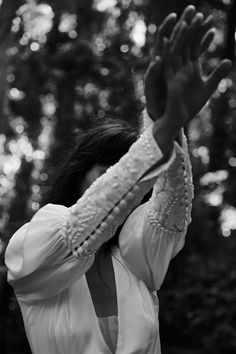 black and white photograph of a woman holding her hands up in the air with trees in the background