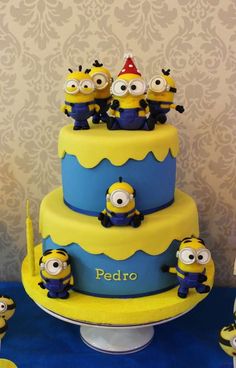 a three tiered cake with minion figurines on top