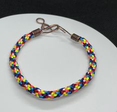 the bracelet is made with multicolored thread and metal clasps on a white plate