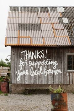 a wooden building with graffiti written on it's side and the words thanks for supporting you local farmer