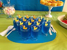 a table topped with glasses filled with blue liquid and yellow rubber ducky hats on top of them