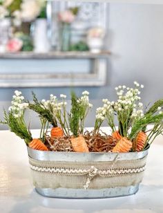 carrots and baby's breath in an old tin container on a table with flowers