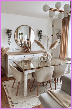 a dining room table with white chairs and a mirror on the wall above it that has feathers in front of it