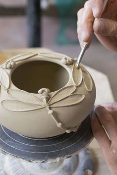 a person is decorating a clay bowl with a spoon