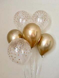 gold and white balloons are arranged in a vase